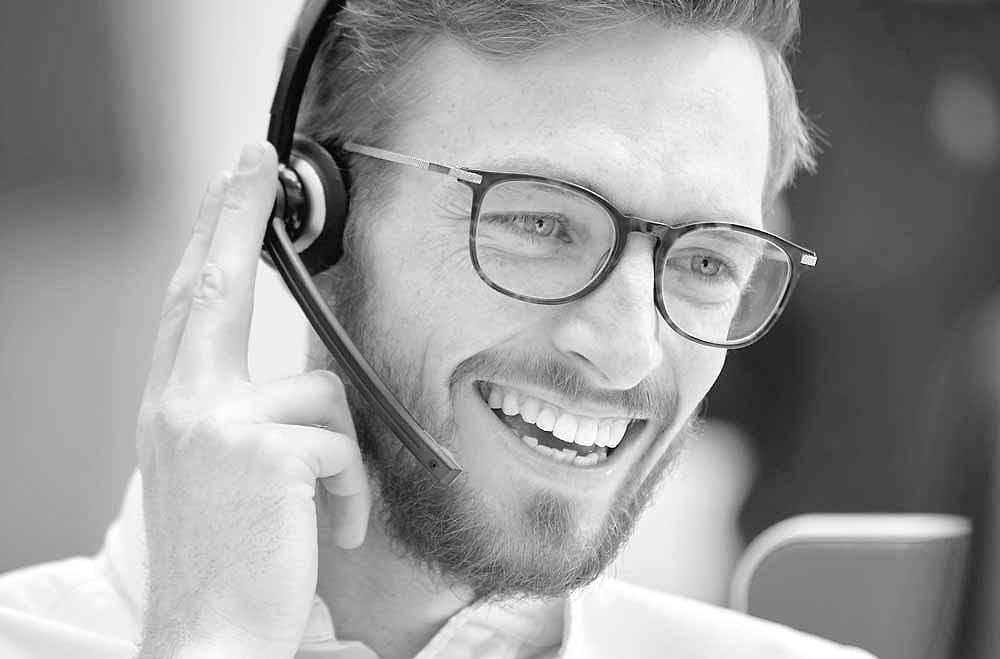 Mitarbeiter mit Headset im Kundentelefonat, Aufnahme in Schwarz und Weiß.